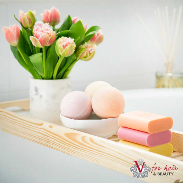 beautiful colourful tilley bath bombs on bath tray with flowers and soaps